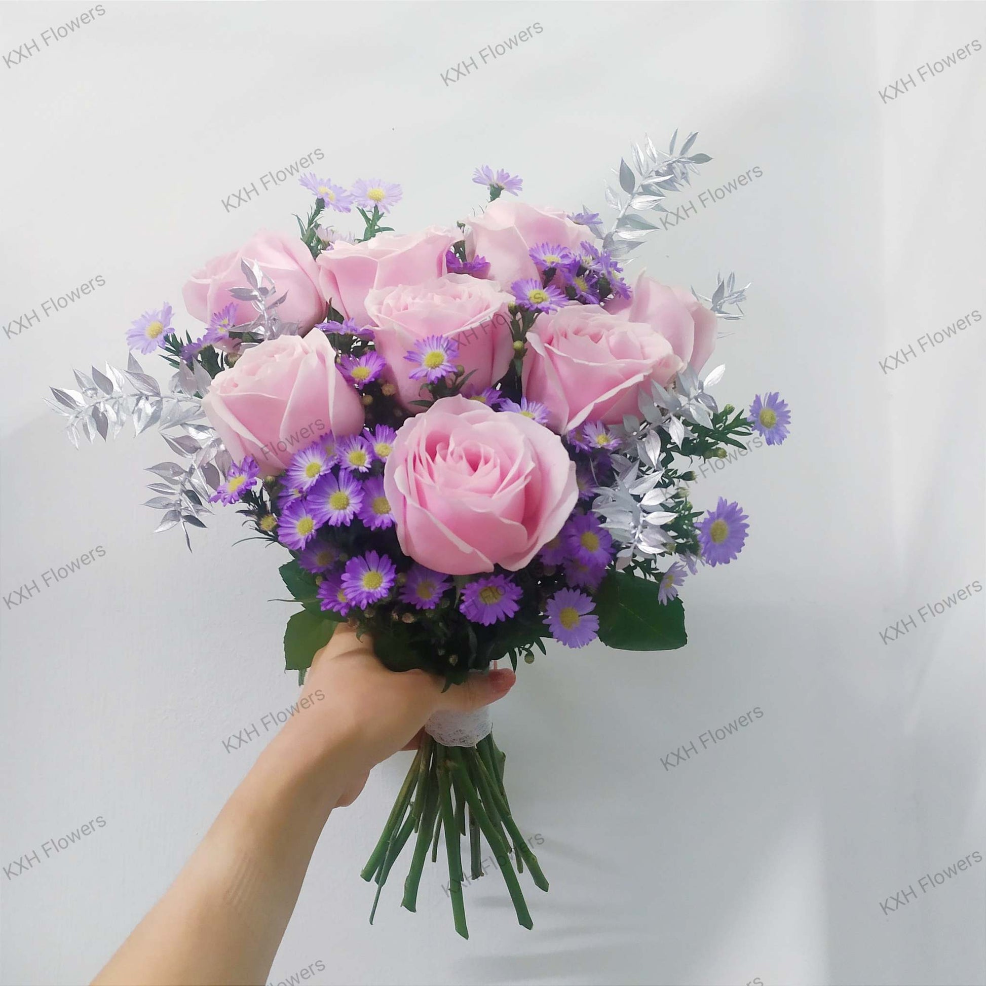 Hand holding elegant bouquet of red and pink flowers