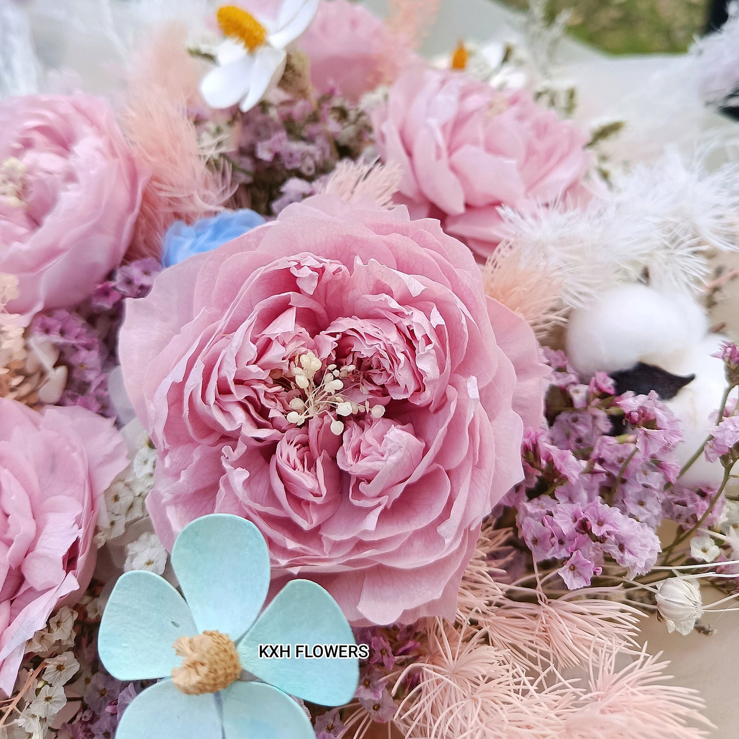 Close-up of a preserved flower bouquet with dusty pink peonies and blue daisy singapore