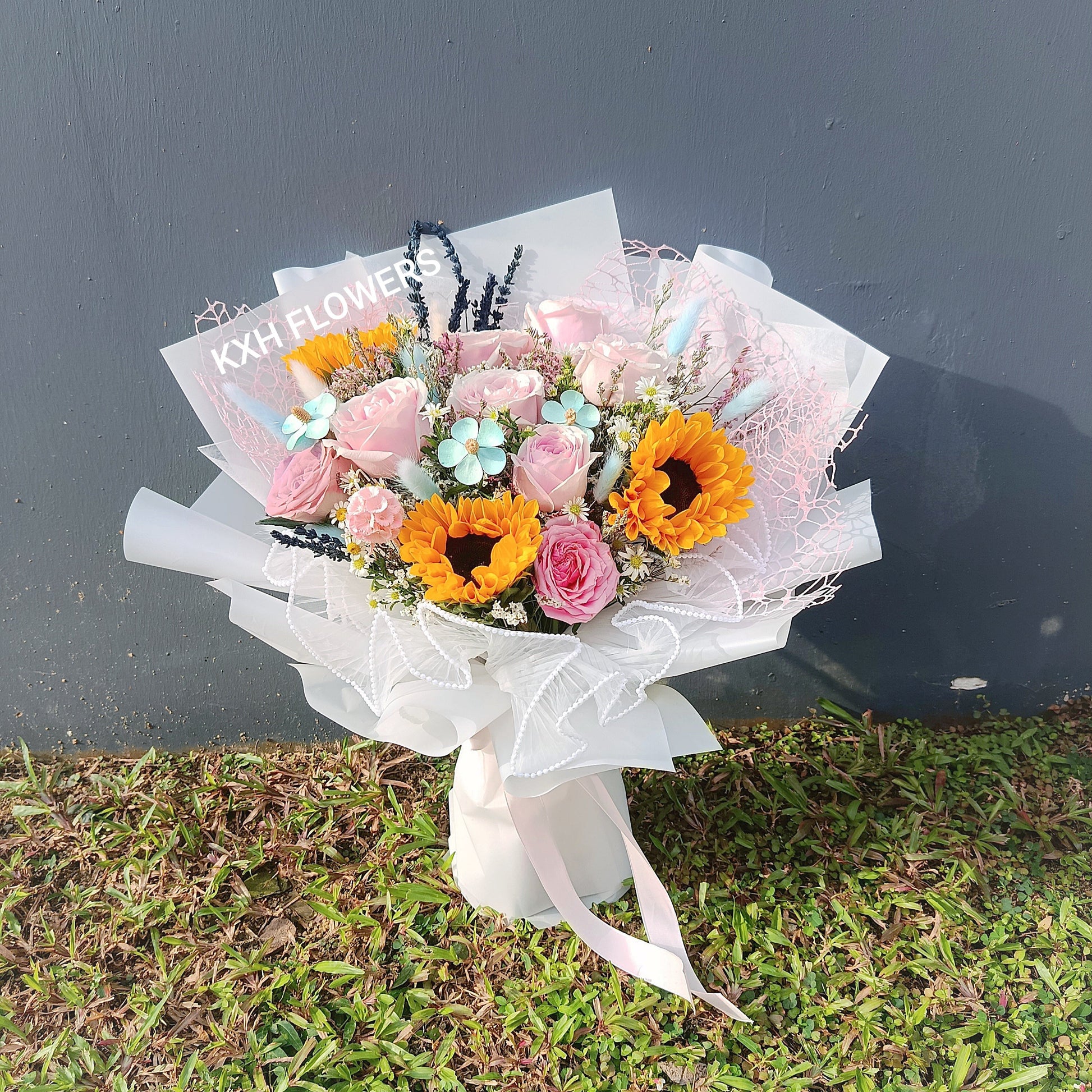 Bouquet of flowers with sunflowers and pink roses on a grassy ground singapore florist