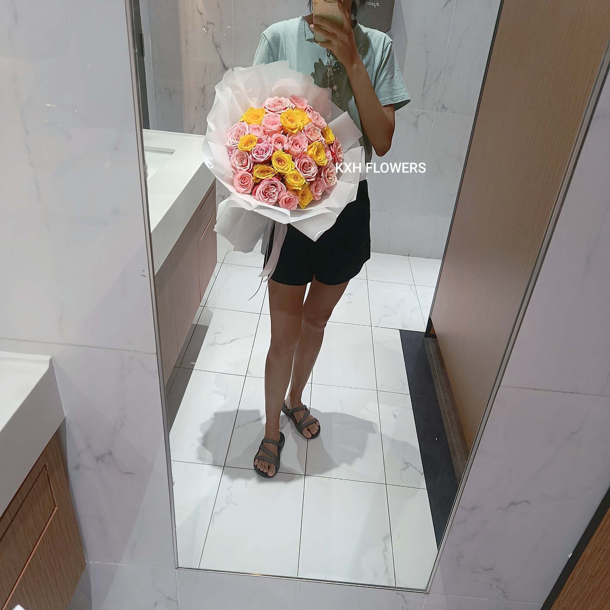 Person holding a bouquet of 30 roses in front of a mirror